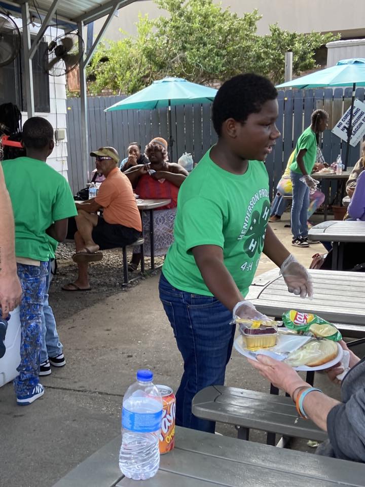 A boy handing someone a plate of food.